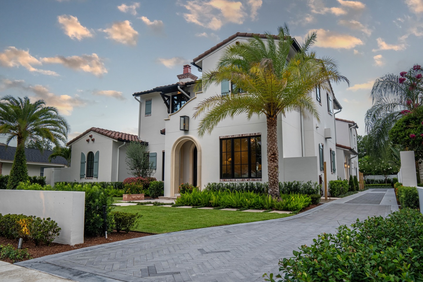 Mediterranean luxury home with paver driveway and lush tropical landscaping by William Thomas Design