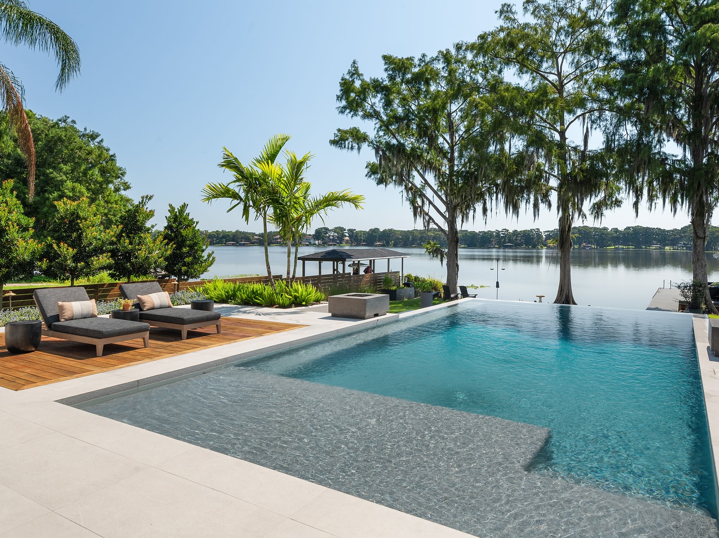 Luxury infinity pool overlooking a lake with tropical landscaping by William Thomas Design in Orlando FL